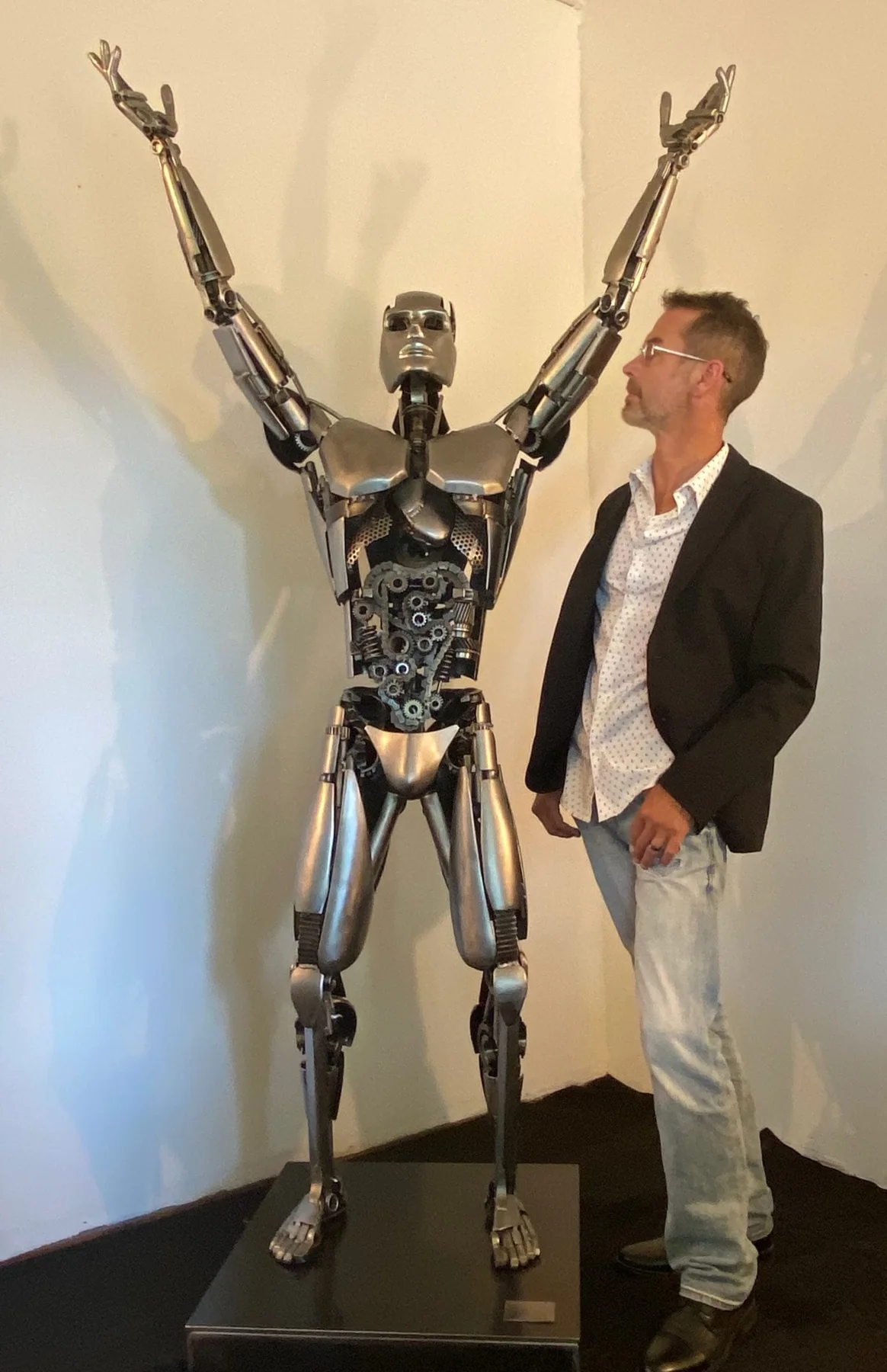 Artist Cory Fuhr standing beside Ben, the sculpture commissioned for the Benessair lobby