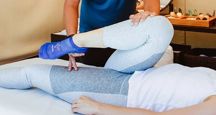 Hands supporting a leg during assisted movement